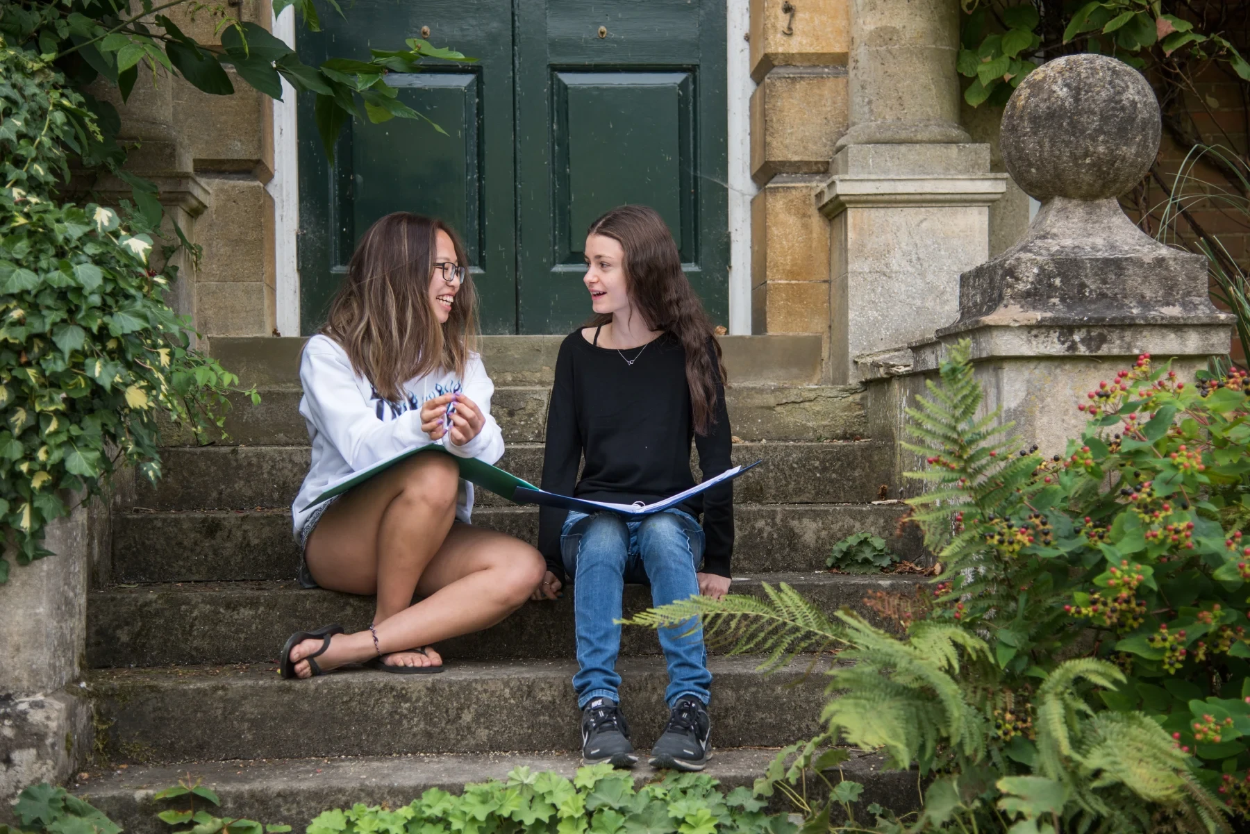 Two students sitting on steps outside college
